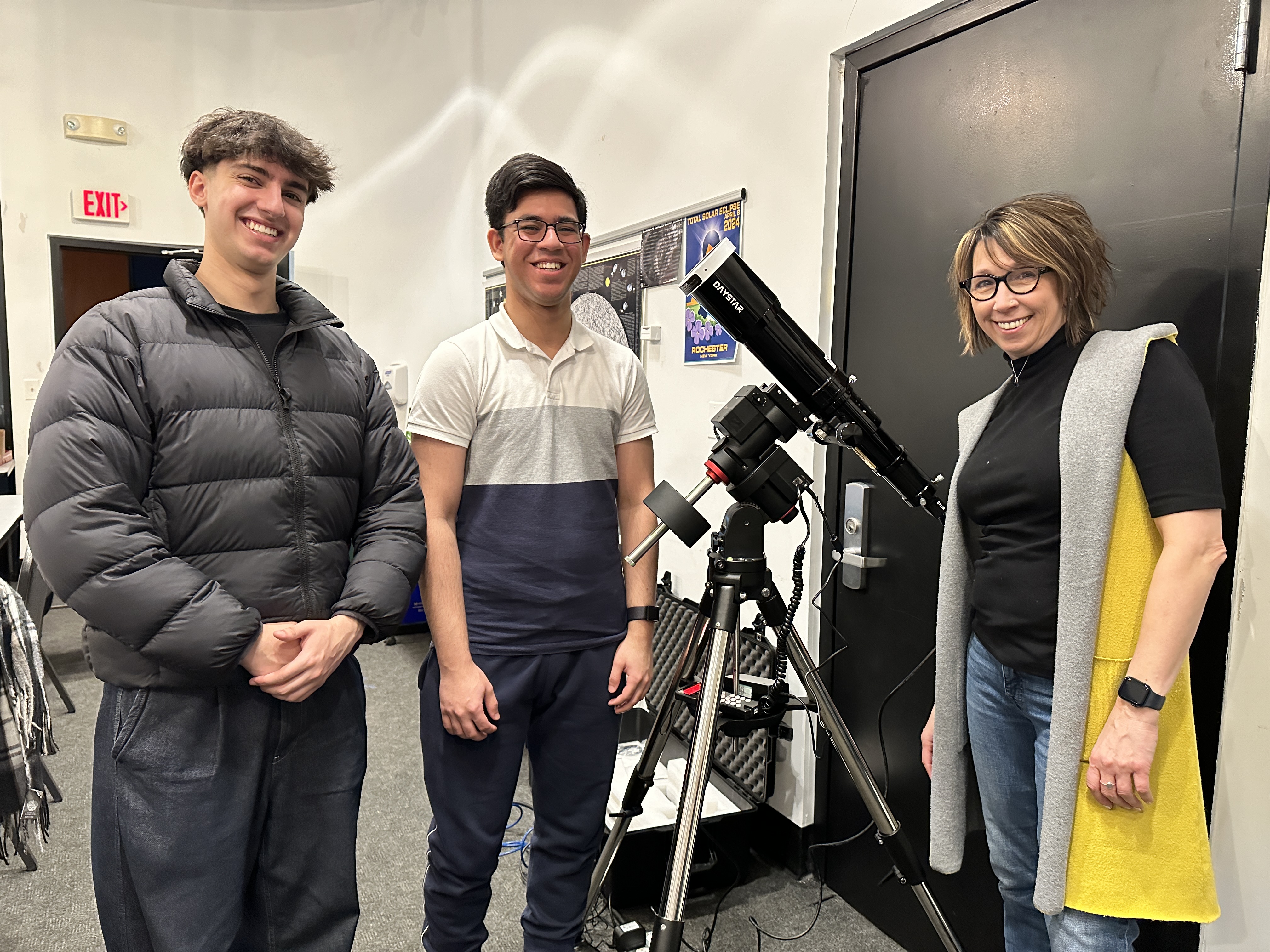 Professor April Luehmann and UR undergrads standing next to a telescope