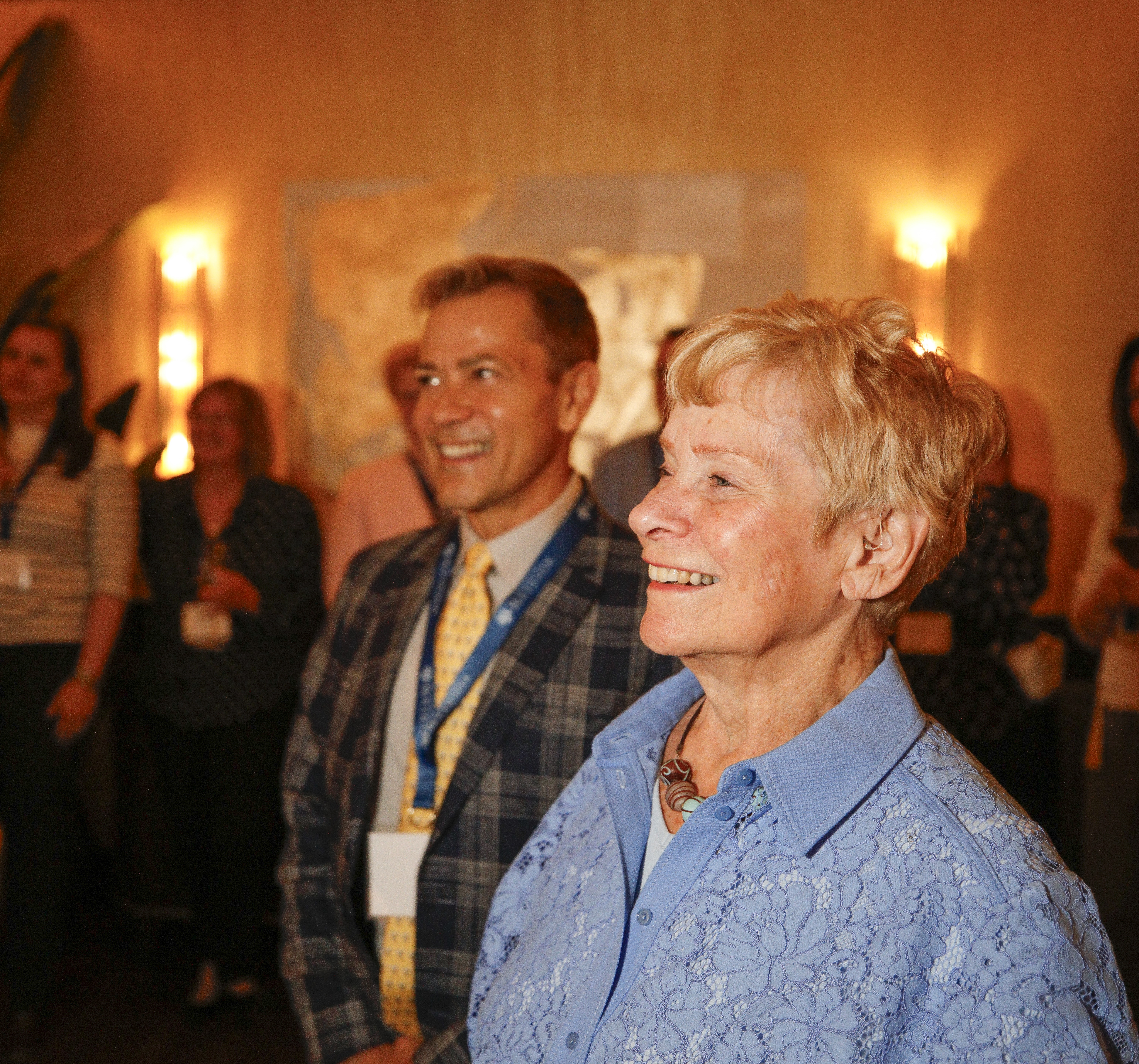 Mary Ellen Burris stands, smiling, at a social gathering.
