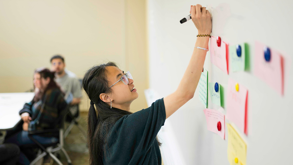 Student writing on white board during class. (URochester photo / J. Adam Fenster)